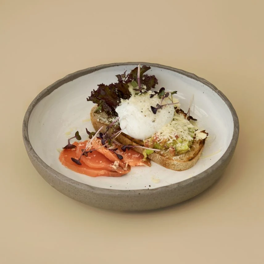 Завтрак GAGARIN GASTRO BAR: тост с яйцом, зеленью и ломтиками рыбы на светлой керамике