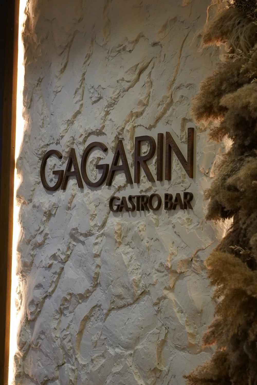 Вывеска GAGARIN GASTRO BAR на фактурной светлой стене с тёплой подсветкой